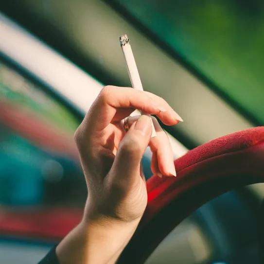 Una mujer sujeta un cigarrillo en el coche