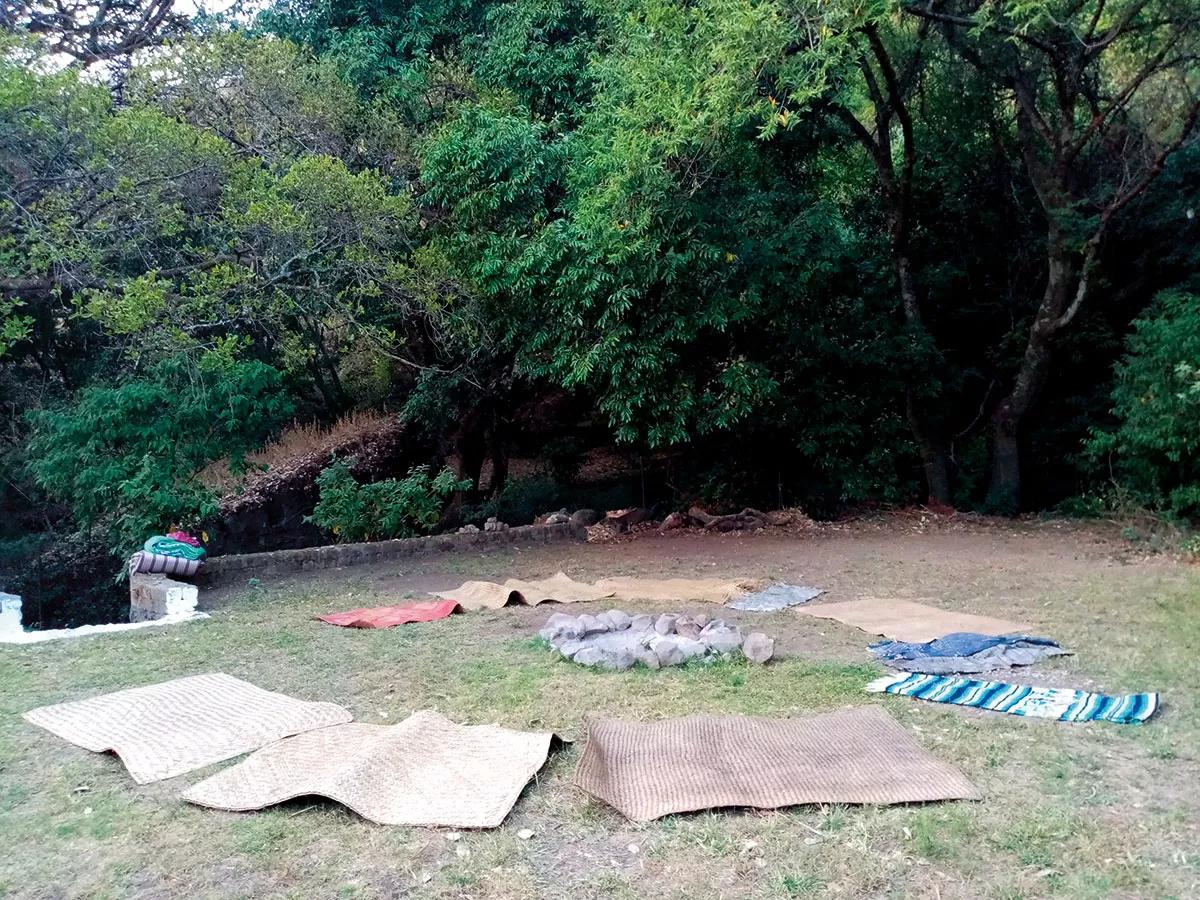 La preparación, unas mantas y unas esterillas dispuestas en círculo alrededor del fuego.